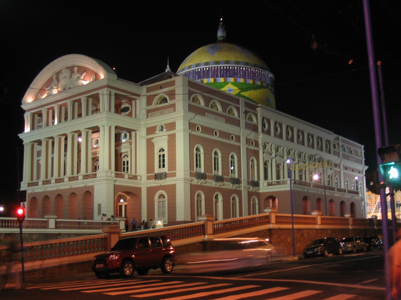 Theatro Amazonas à noite, com a cúpula nas cores da bandeira e a fachada rosa, em Manaus.